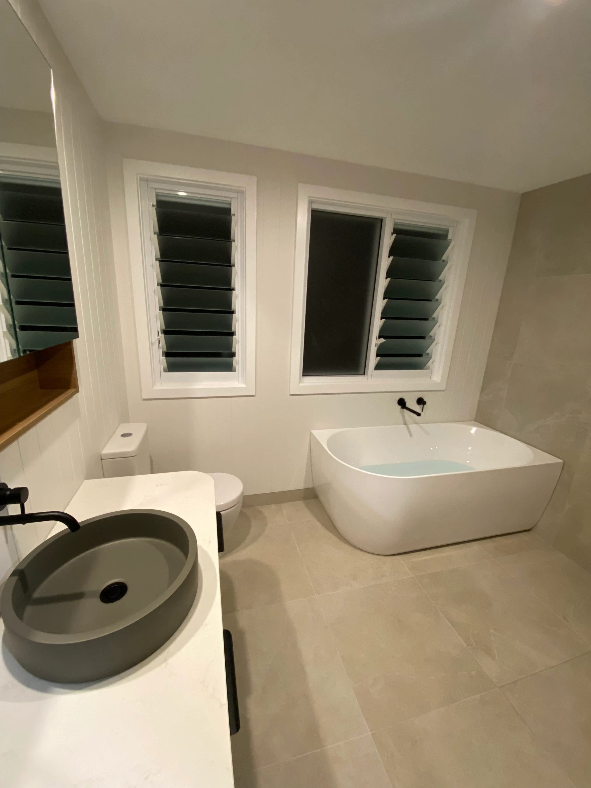 Minimalist bathroom with vessel sink, toilet and freestanding bath