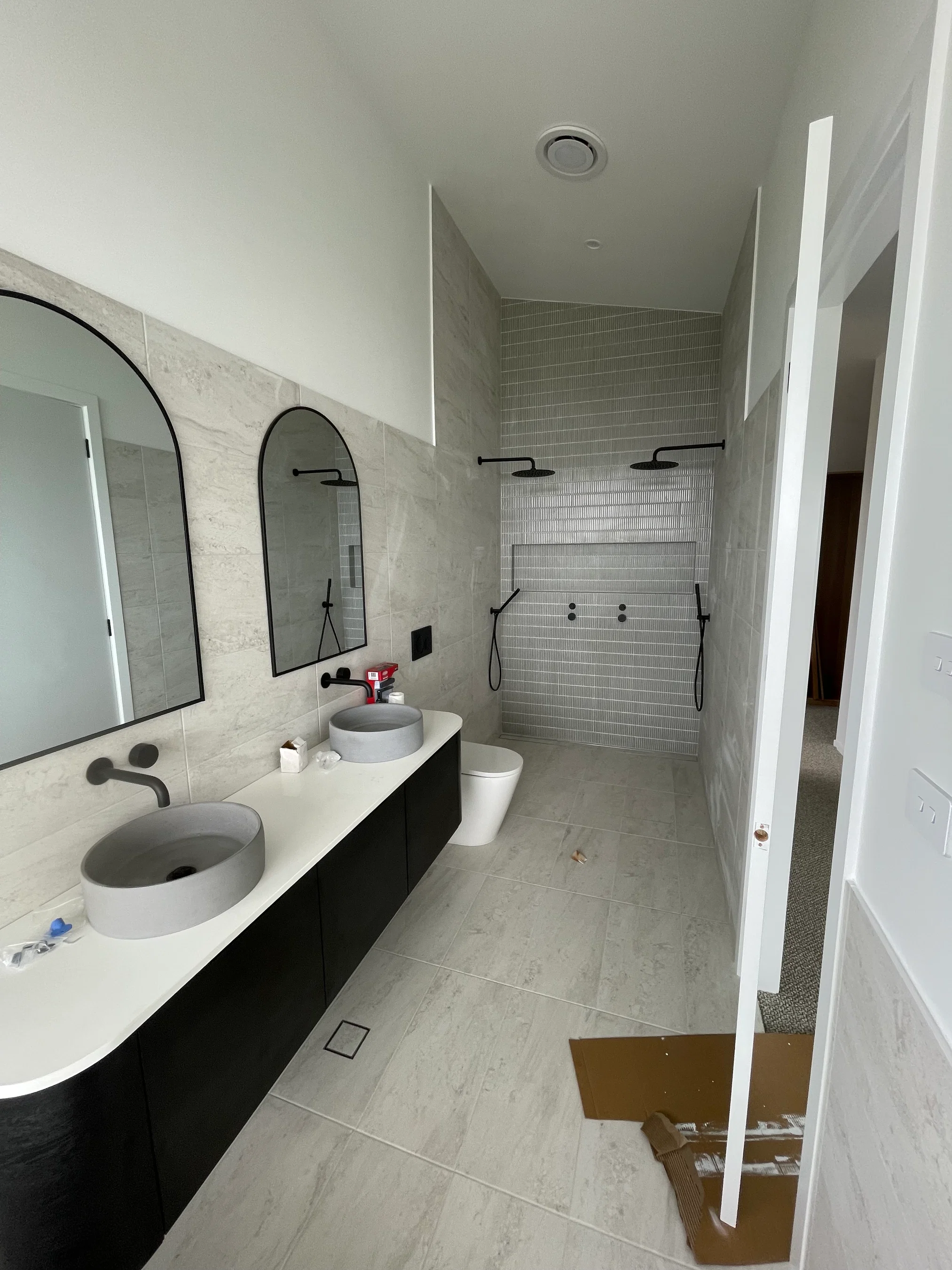 Long ensuite with double vessel sinks, arched mirrors and walk-in shower