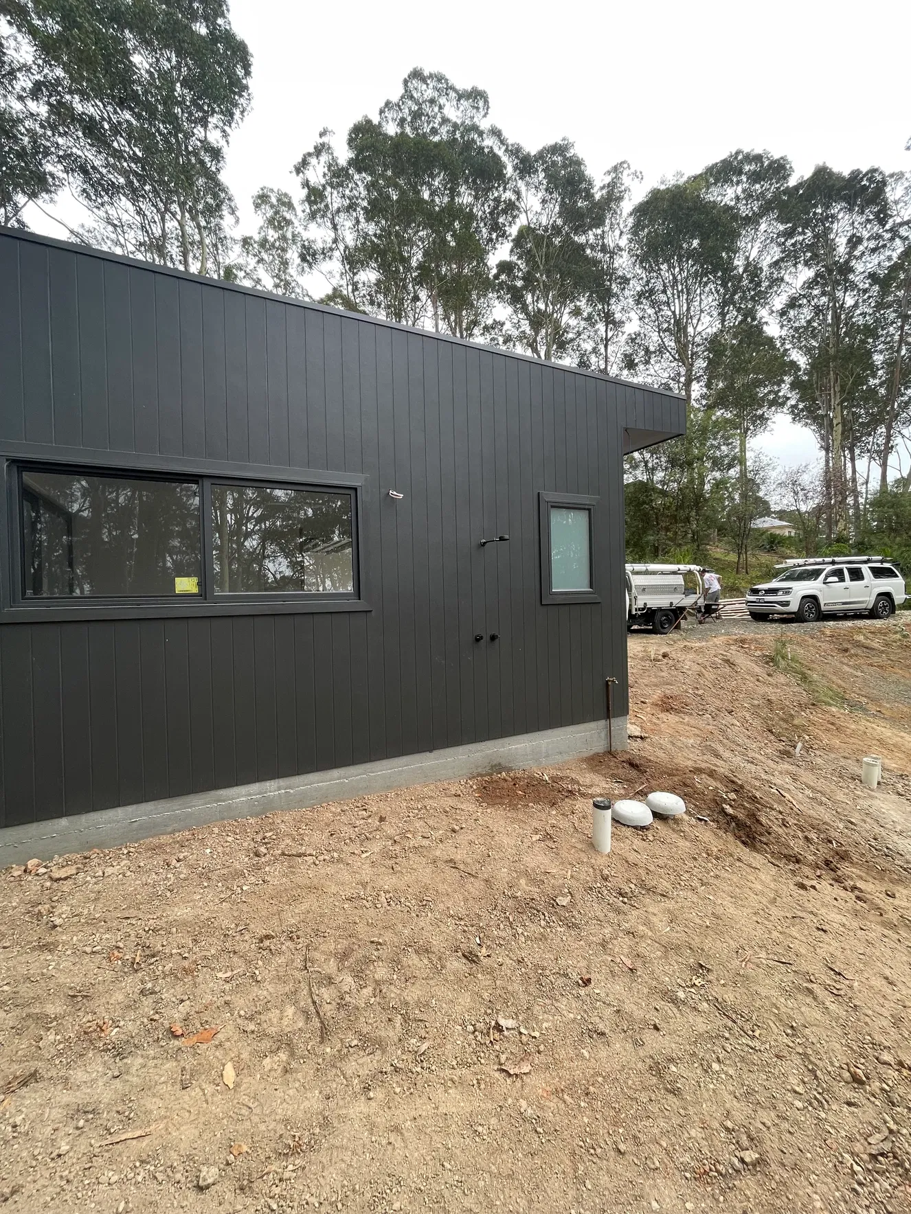 Dark cladding new build with PVC service pipes at foundation