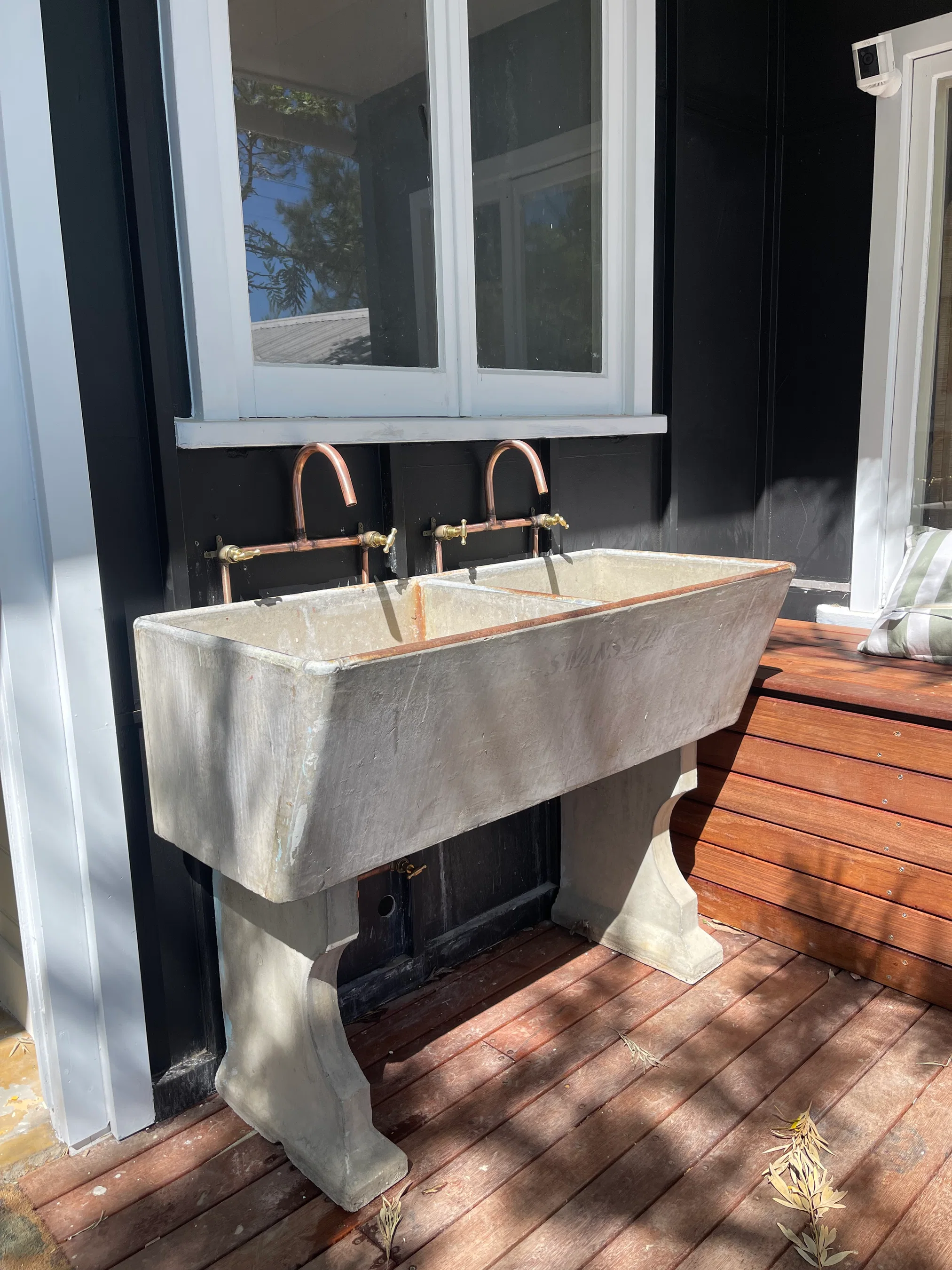 Double outdoor concrete sink with copper tapware on timber deck