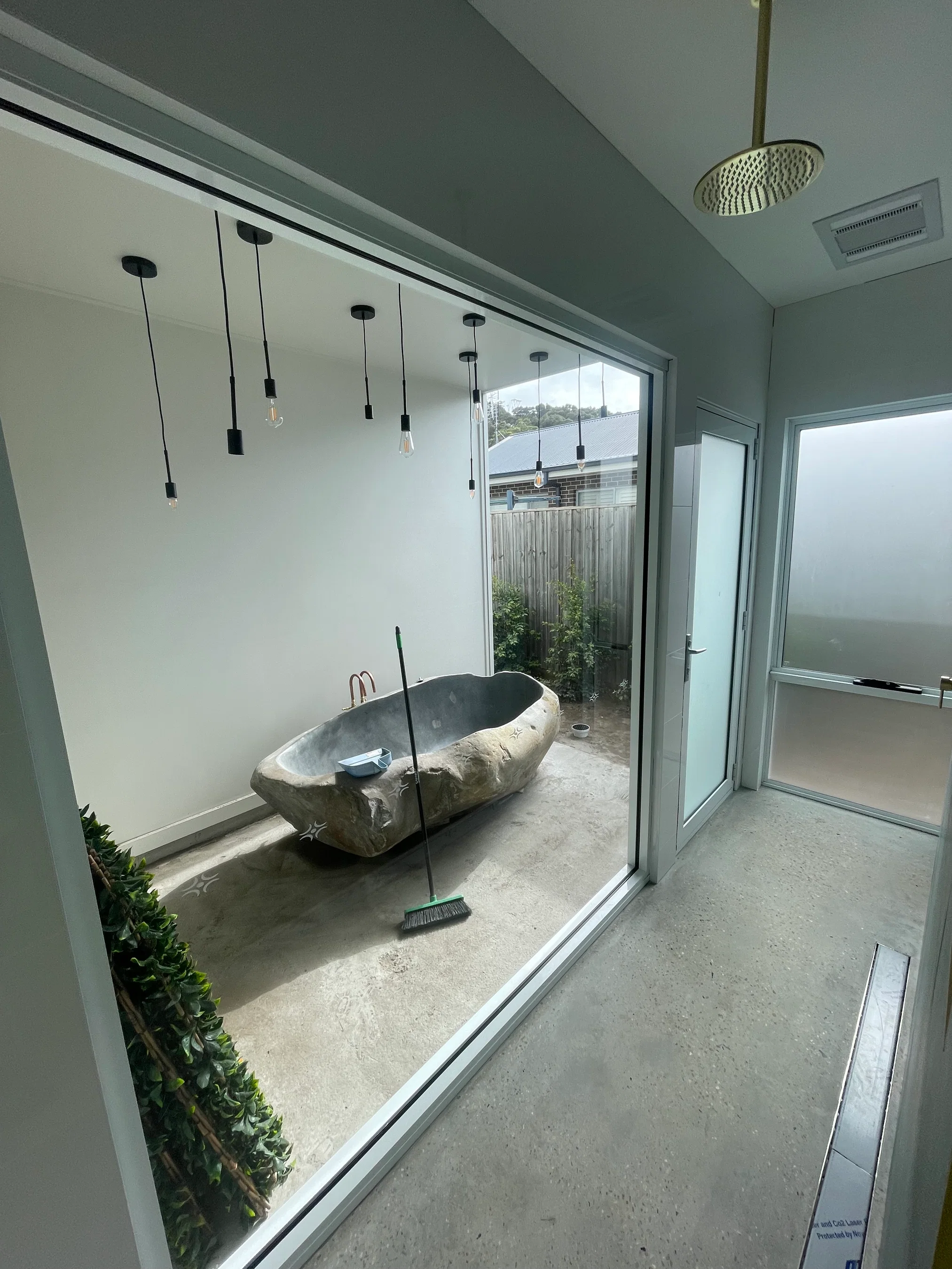 Natural stone bathtub in indoor-outdoor courtyard with pendant lighting