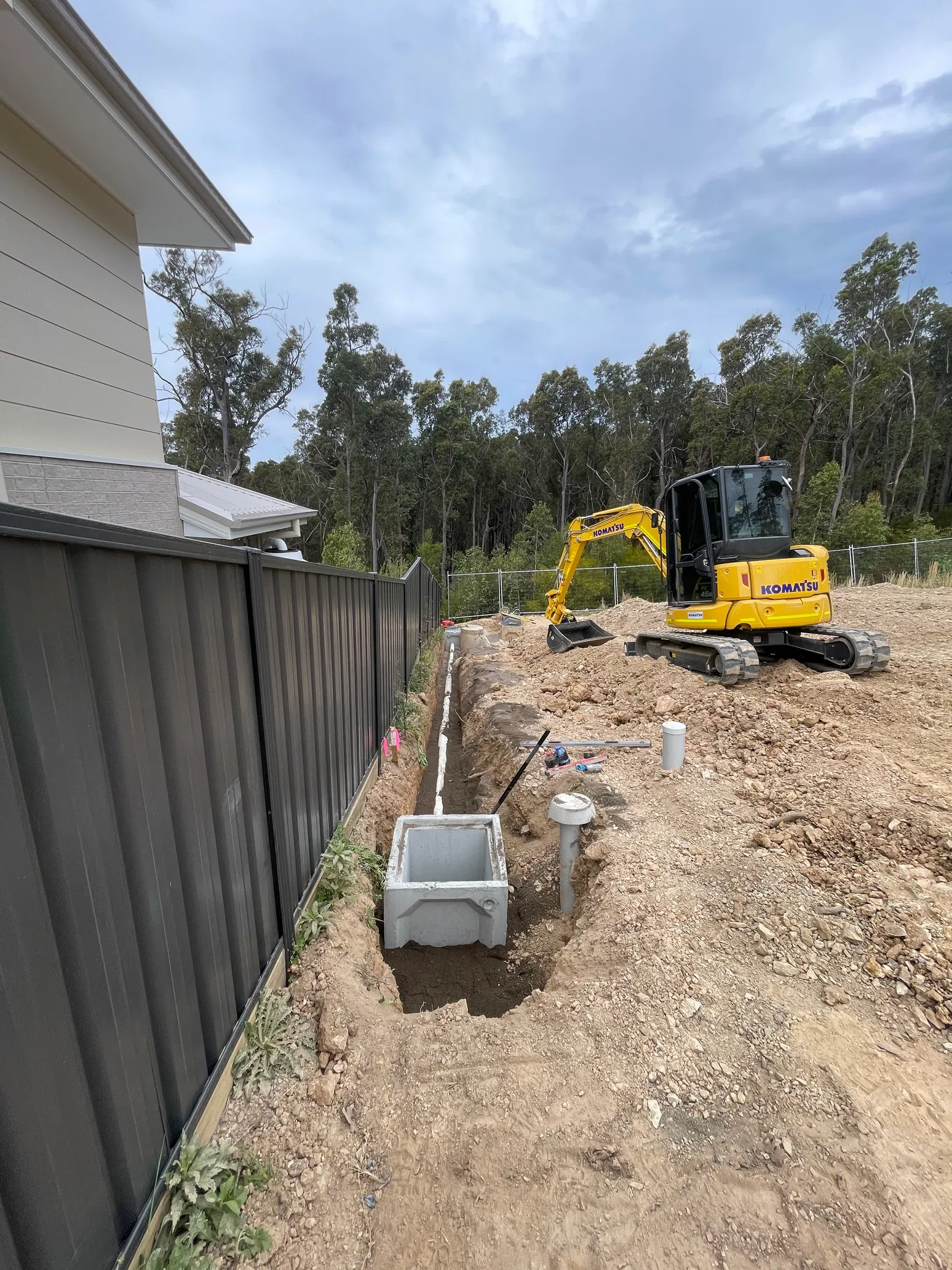 Concrete stormwater pit and PVC pipe trench with mini excavator